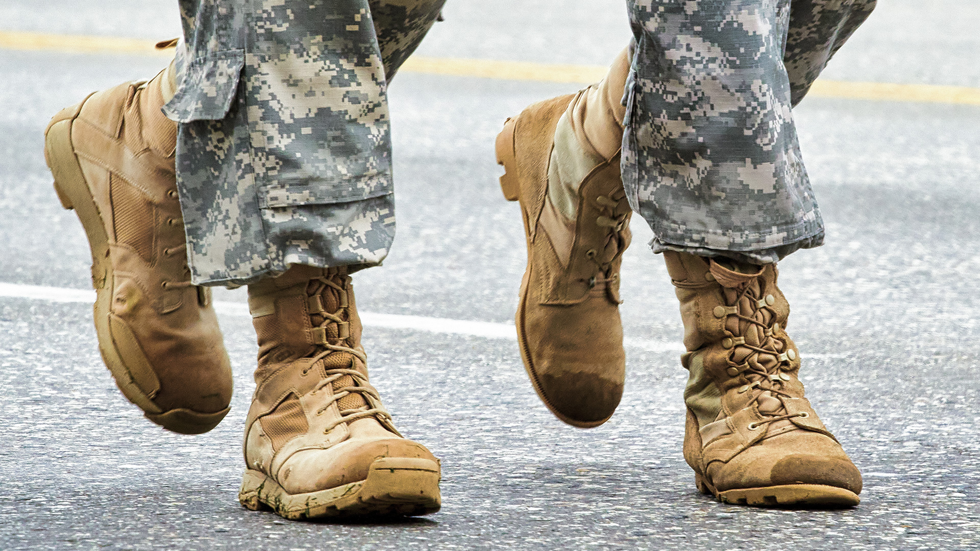 two people pictured below the knee walking and dressed in camo pants and tan boots