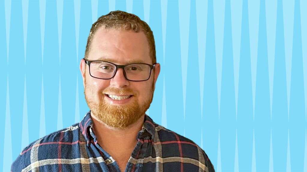 smiling bearded man with plaid button-up shirt and glasses