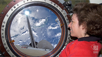 astronaut ellen ochoa looking out of spacecraft window down at some clouds